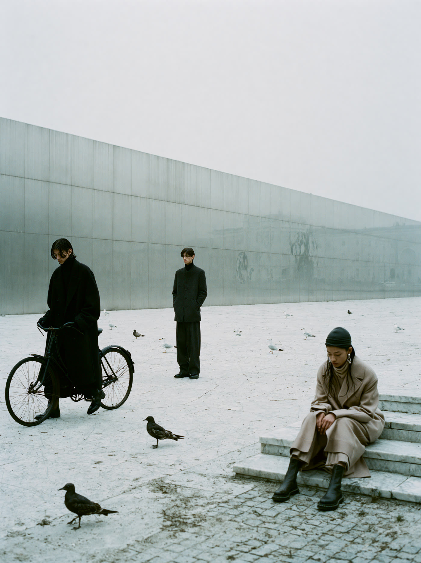 Three figures on a bench with pigeons