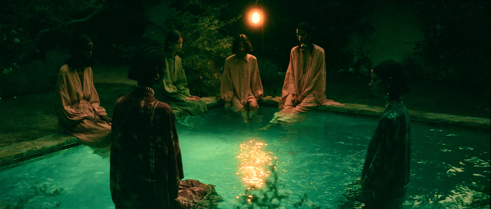 Four models gathered around a glowing pool at night