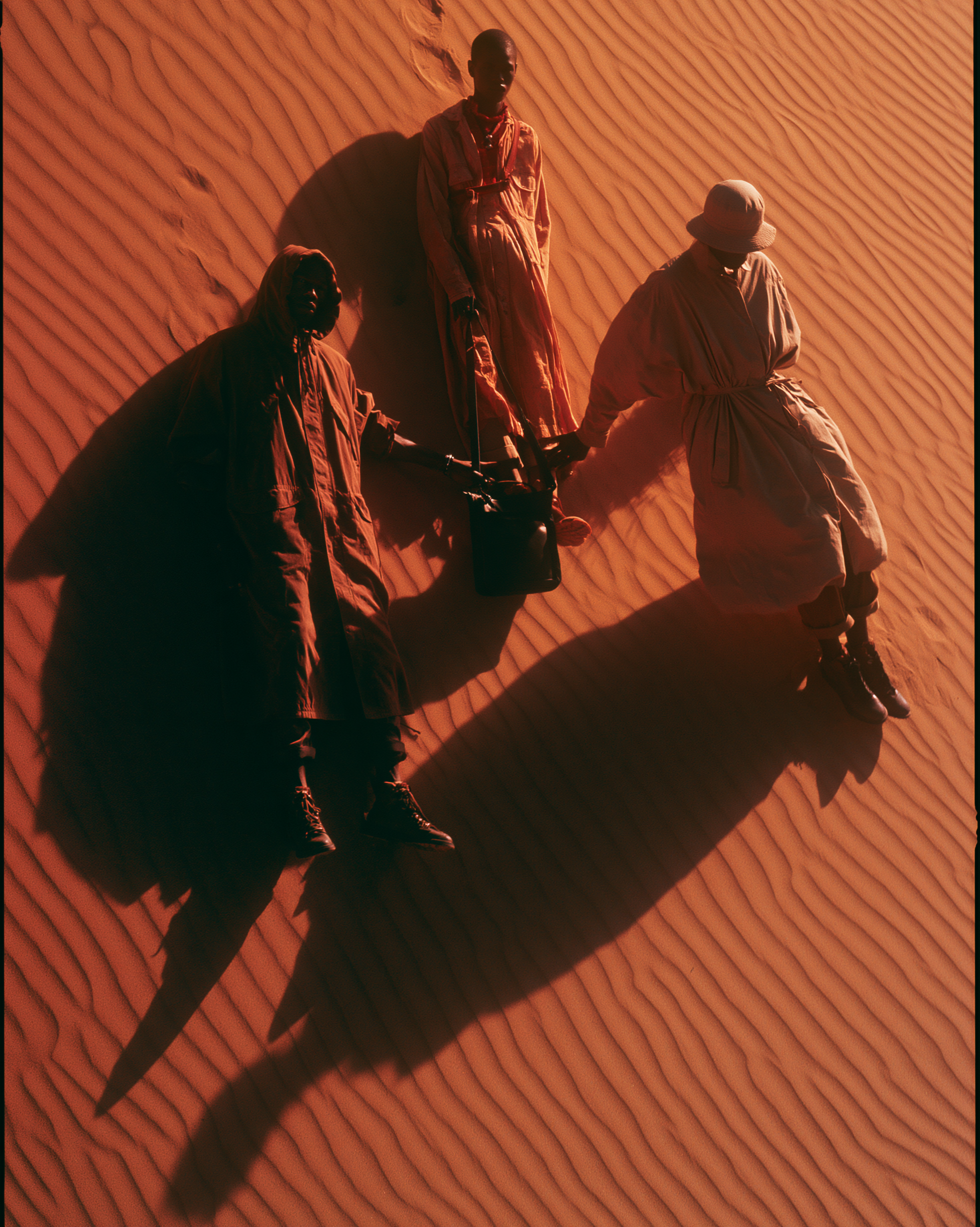 Three models lying on the dune photographed directly from above