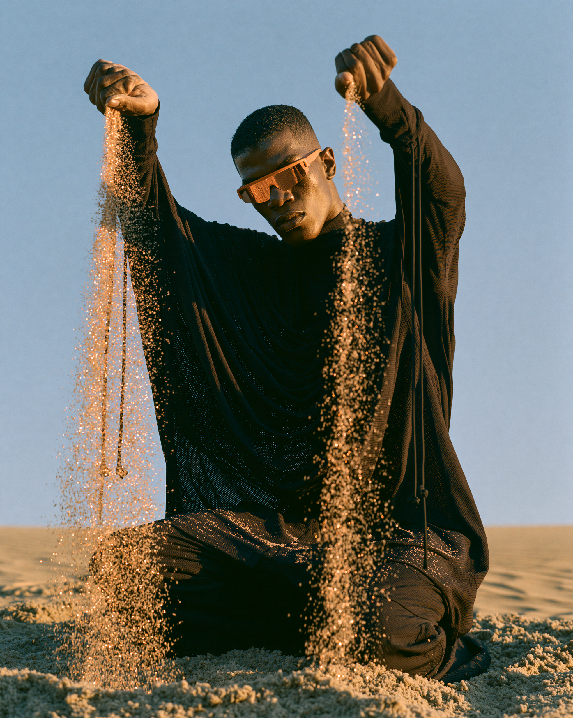 Kneeling model pouring sand from both fists