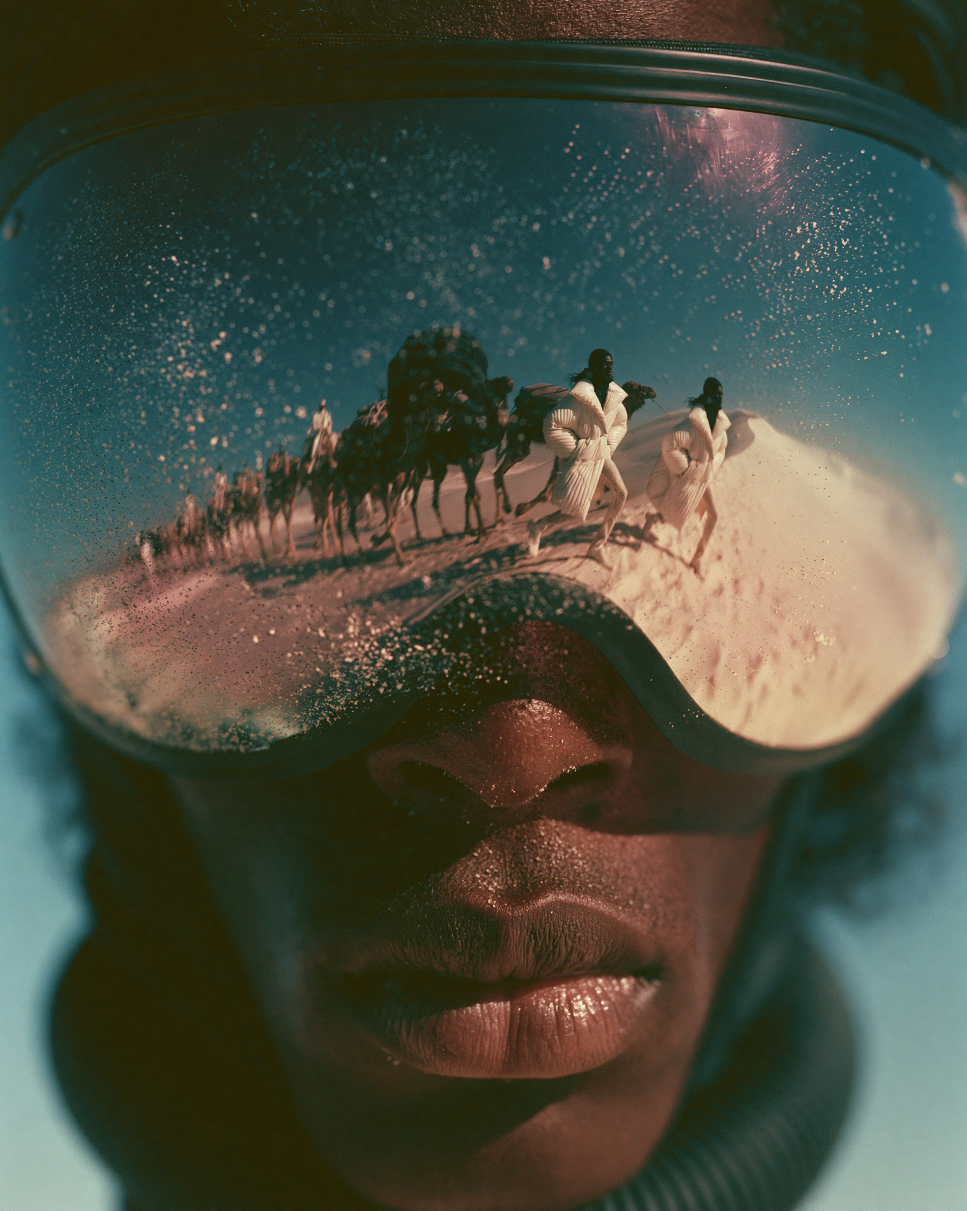 Extreme close-up of goggles reflecting the camel caravan on the dune