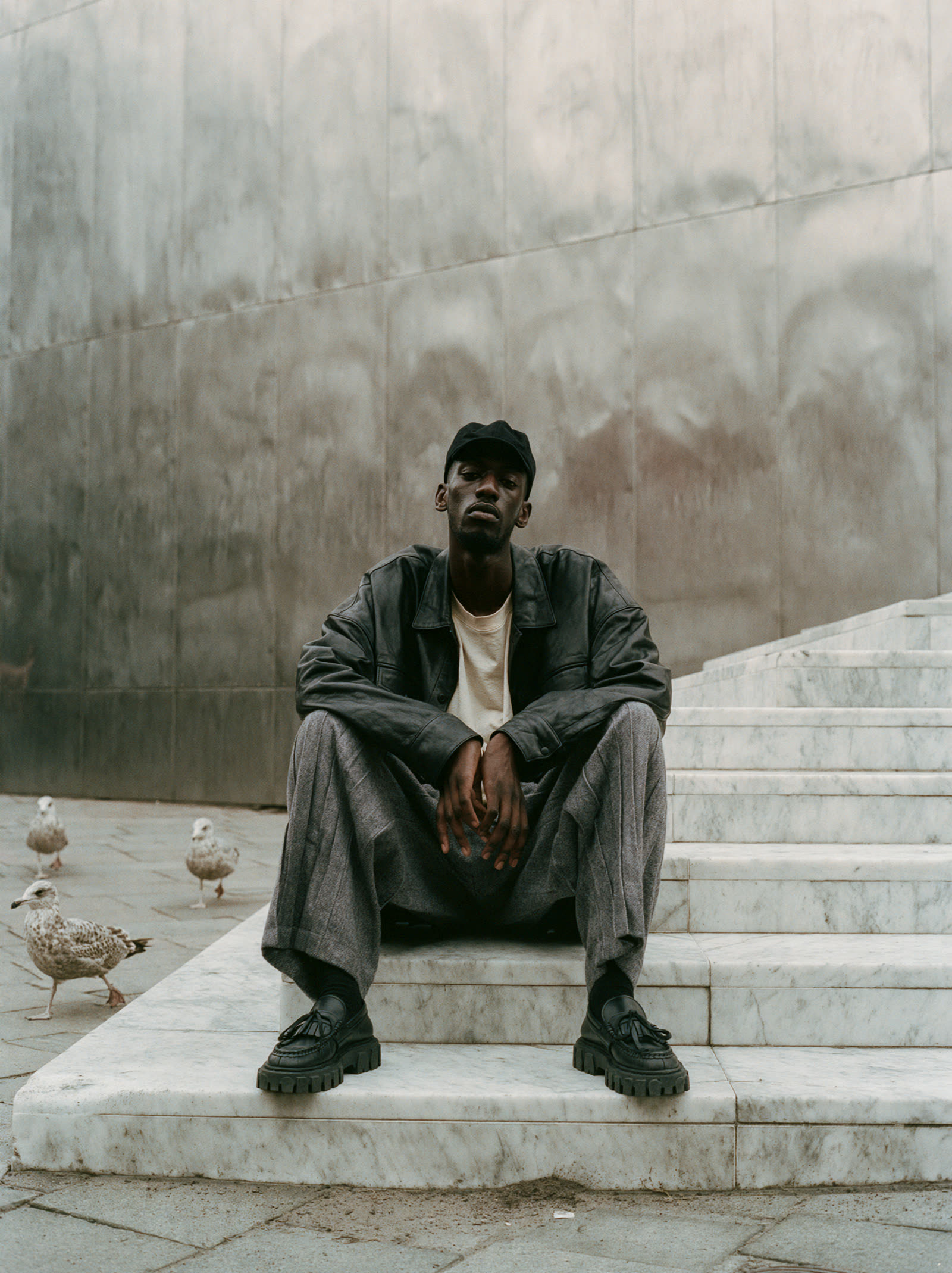 The same man seated on marble steps
