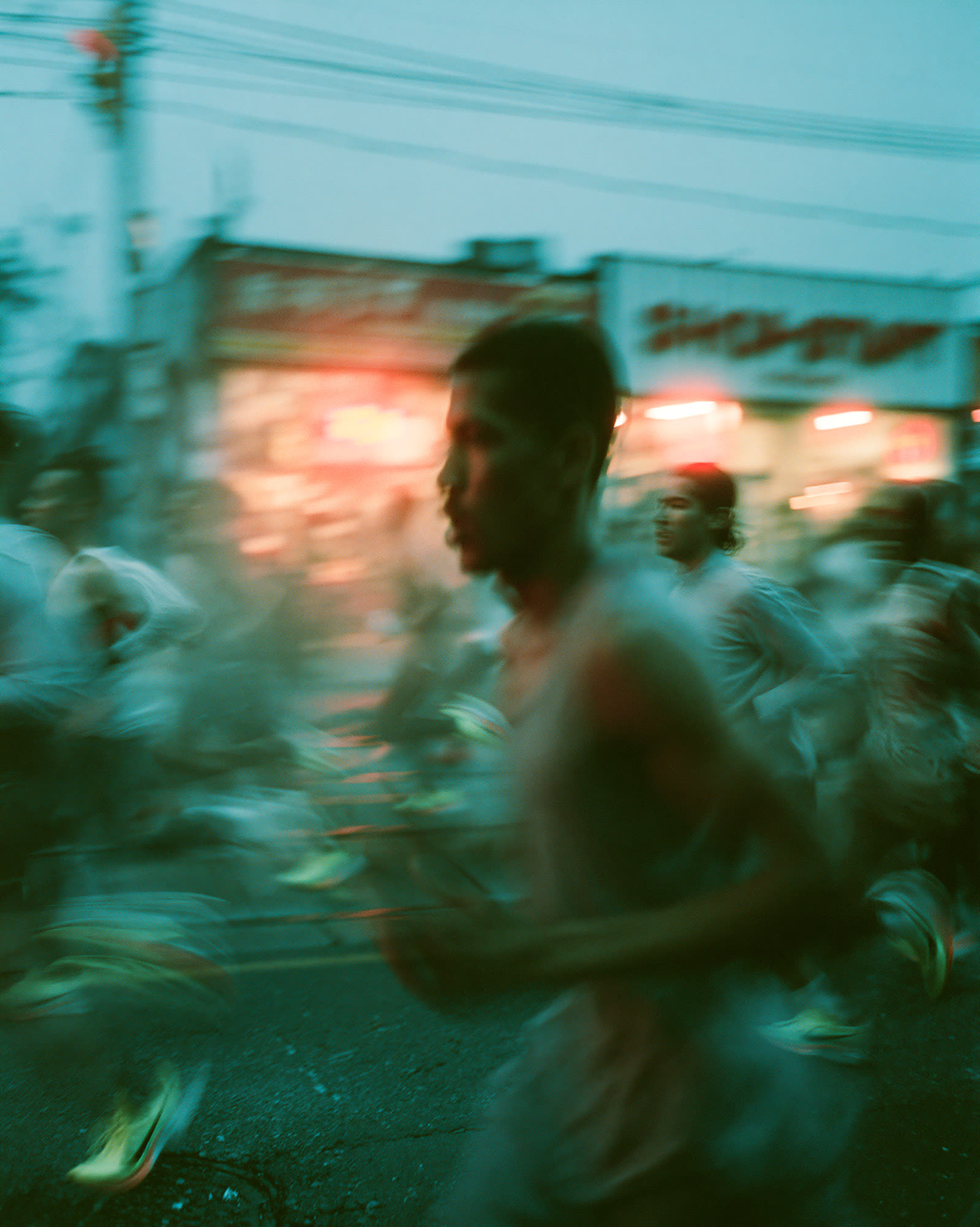 Runners blurred past glowing storefronts at night