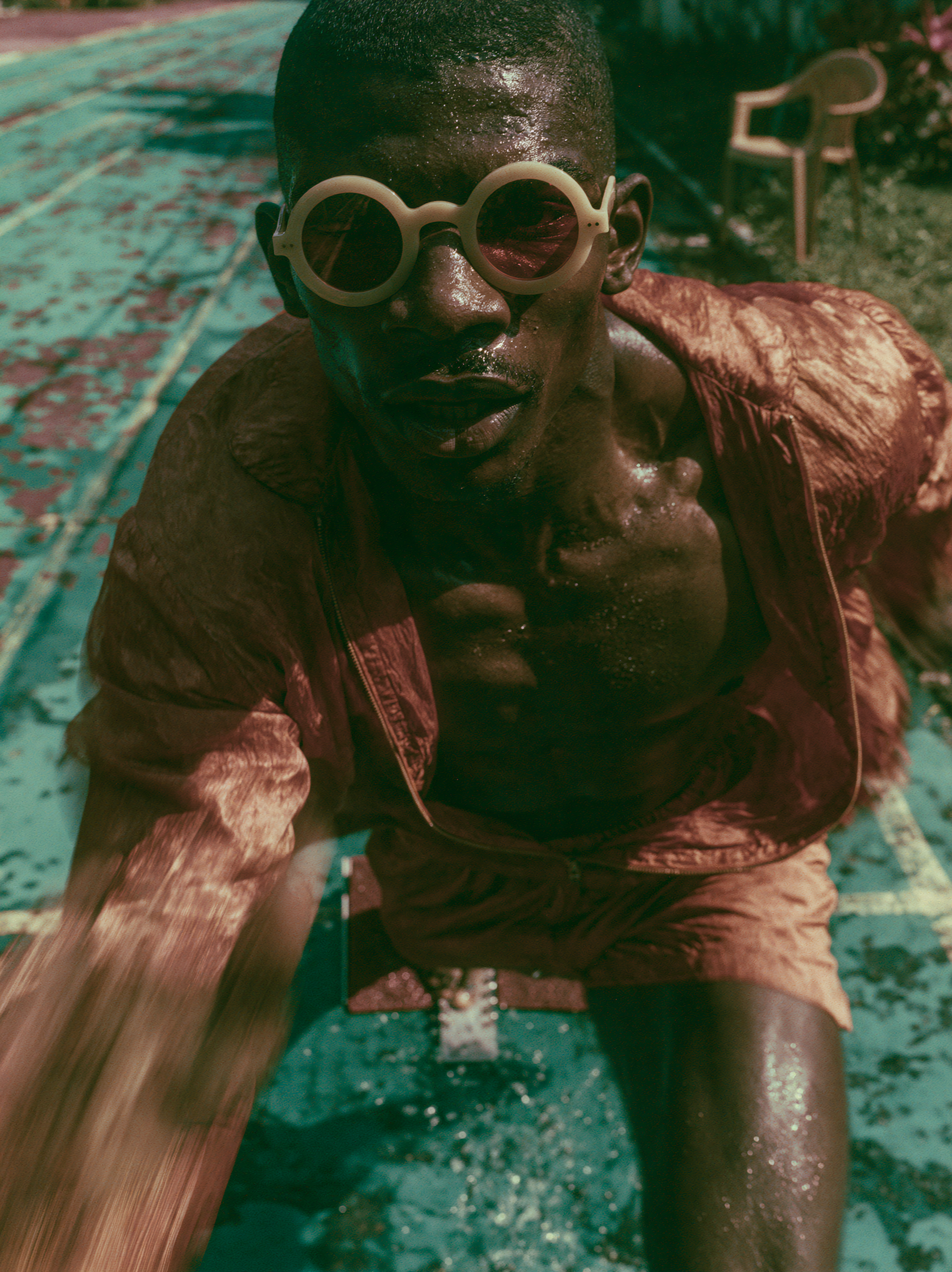 Sprinter in rust silk crouched at the start on a cracked teal pool floor
