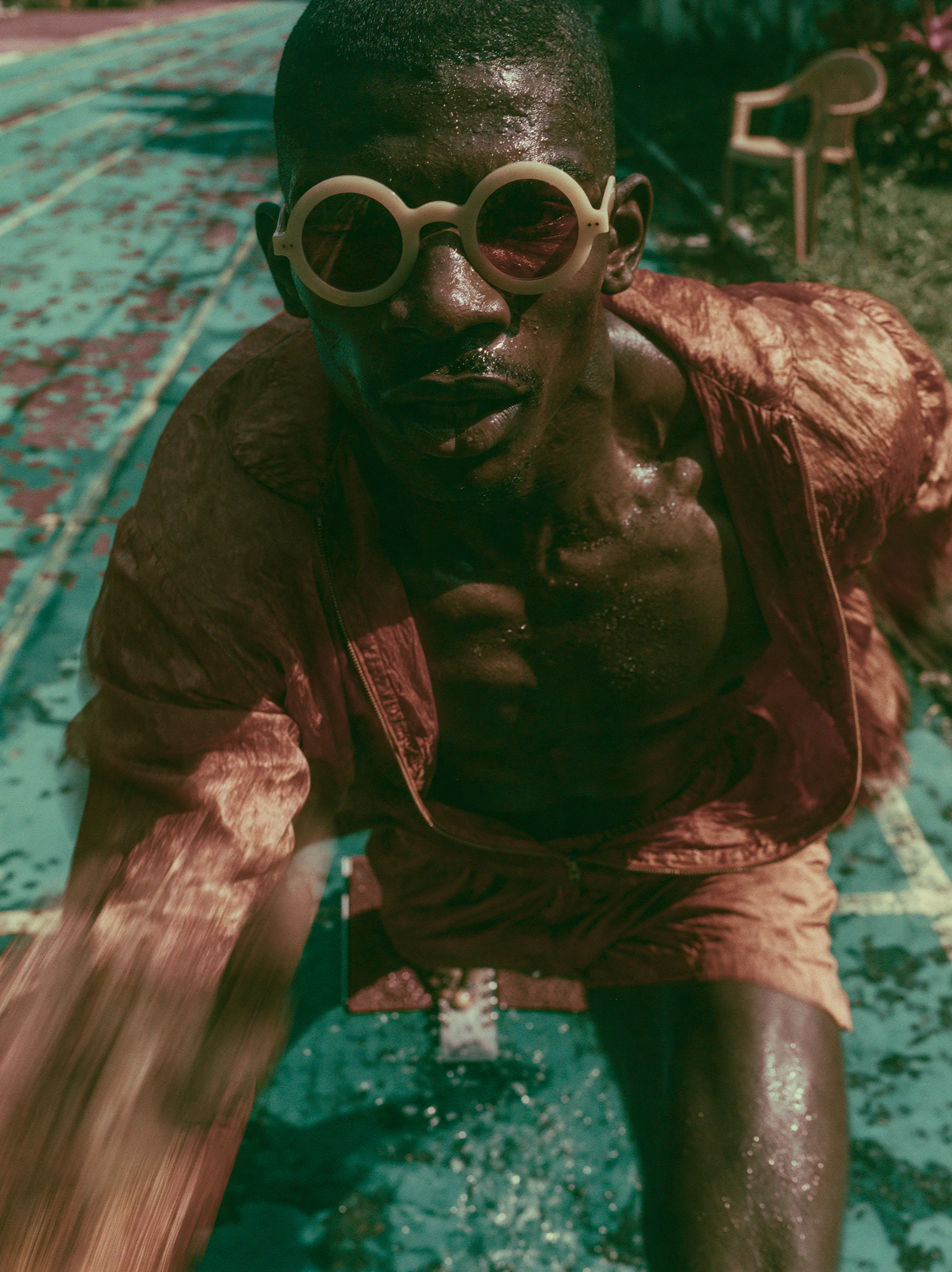 Sprinter in rust silk crouched at the start on a cracked teal pool floor